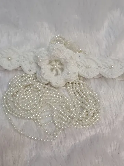 This beautiful headband is designed to match my pearl-accented booties, featuring a large crochet flower with a cascade of delicate pearl strings.
