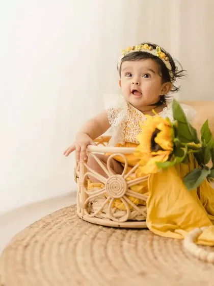 A full view of our sunflower-themed sitter session setup. The baby sits in a basket on a jute rug, surrounded by pampas grass and boho elements.