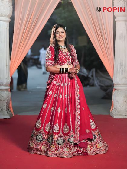 A full-length view of a happy bride in a stunning red lehenga. I ensure every bride feels like a queen without the financial stress of buying a bridal outfit.