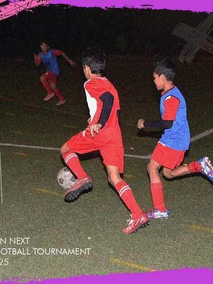 A player dribbling the ball during a night match at the GenNext Football Tournament.