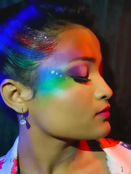 This profile shot under colored lighting highlights the glitter detail and the smooth transition between the different hues in this creative Holi makeup.
