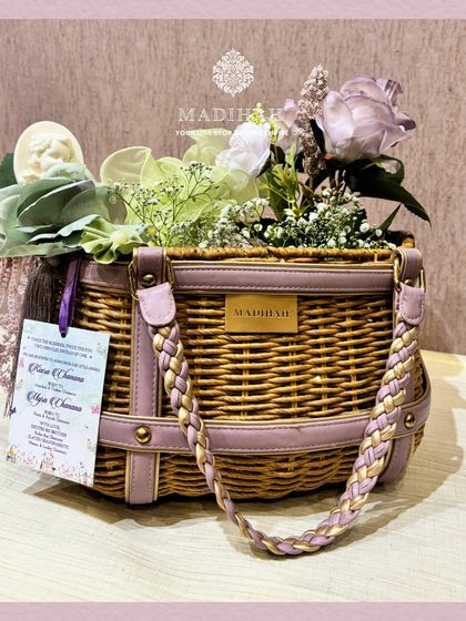 A clean, studio-style shot of the Cane Arrival Basket. This image clearly displays the design, from the branded Madihah plate to the delicate floral arrangement and personalized tag.