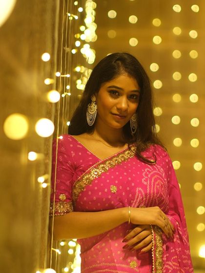 Framed by a curtain of festive lights, this portrait captures the magical glow of Dev Deepawali and the elegance of traditional Indian attire.