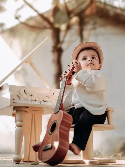 A little musician with his guitar. This creative setup with a miniature piano and guitar is perfect for capturing a child's budding love for music.
