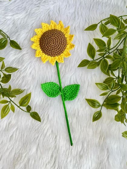 A single-stem crochet sunflower with two bright green leaves. It’s simple, elegant, and full of handmade charm.