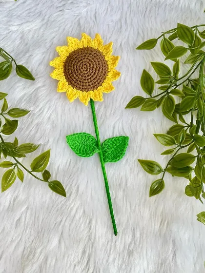 A single-stem crochet sunflower with two bright green leaves. It’s simple, elegant, and full of handmade charm.