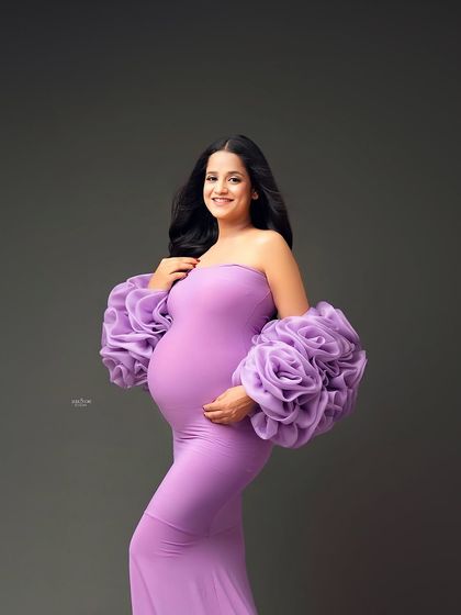 A smile that lights up the whole studio. This shot captures the pure happiness of pregnancy, and the lavender gown is the perfect complement.