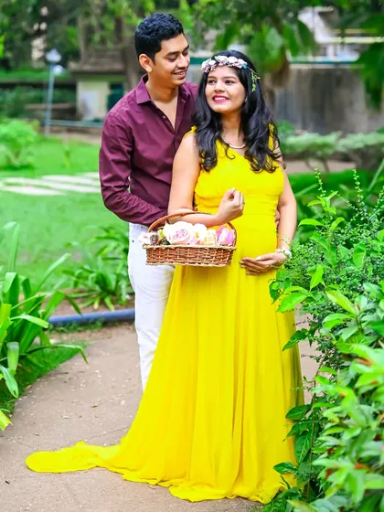 A sweet couple's portrait surrounded by greenery. The mom-to-be holds a basket of flowers, adding a touch of rustic charm.