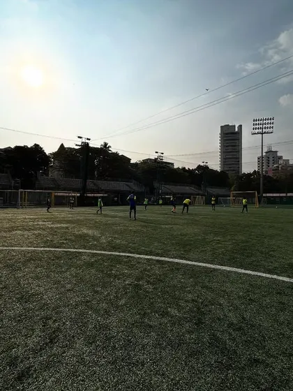 A wide shot of the training ground under a bright sun, with players engaged in drills. This image represents our core values: no shortcuts, just passion, practice, and progress.