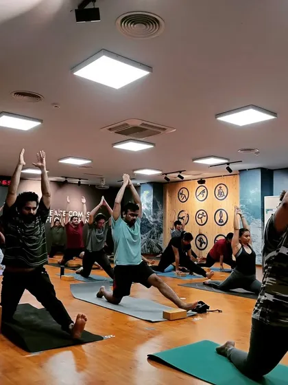 A dynamic moment in class with students in various stages of a low lunge flow. It shows the diversity of movement within a single guided sequence.