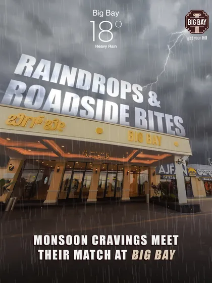 Monsoon cravings meet their match at Big Bay. This dramatic image shows our well-lit entrance standing strong against a rainy, stormy sky, a perfect shelter for travelers.