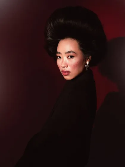 A three-quarter portrait that showcases the incredible volume and shape of the avant-garde hairstyle. The lighting is carefully placed to create depth and shadow.