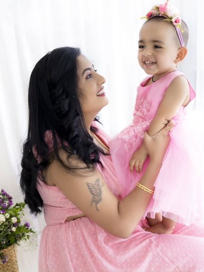 A beautiful, happy moment between a mother and her daughter during a Mother's Day mini-session. Both are dressed in matching pink, surrounded by flowers.