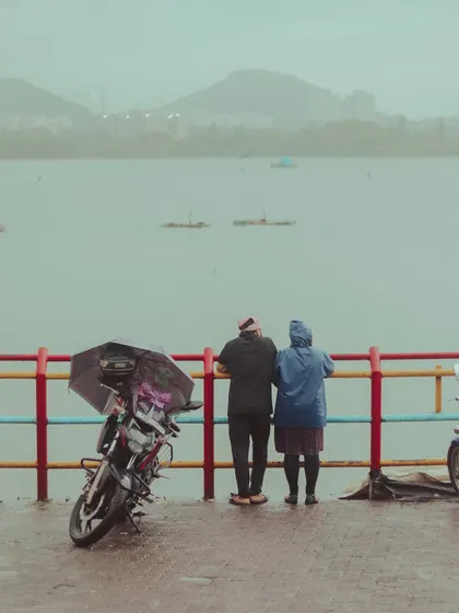 A couple finds a quiet spot by the railings at Powai Lake, their bike parked nearby. It's these simple, shared moments that make the monsoon in Mumbai so romantic.