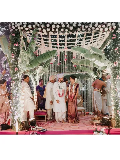 A beautiful moment from a traditional South Indian wedding, complete with cold pyros. The mandap is decorated with banana leaves and white florals, blending cultural elements with modern celebratory touches.