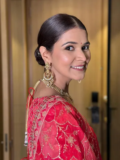 A close-up of Aditi's classic bridal beauty. Her makeup features a soft, matte finish with defined eyes, perfectly complementing her traditional red attire.