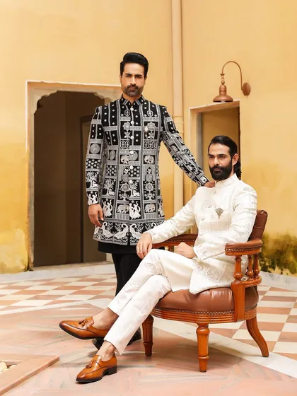 We cater to every style, from timeless tradition to modern elegance. This image captures that duality perfectly, featuring a classic off-white embroidered sherwani alongside a contemporary black and white Indo-Western piece with unique block print designs.