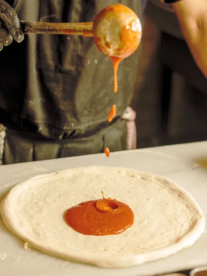 Painting the canvas of flavor, one dollop of sauce at a time. The start of another delicious pizza.