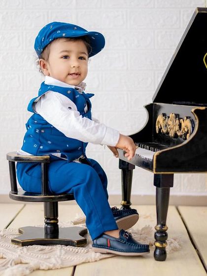 This little gentleman is ready to play a tune. Our piano setup is a classic and elegant theme for toddlers.