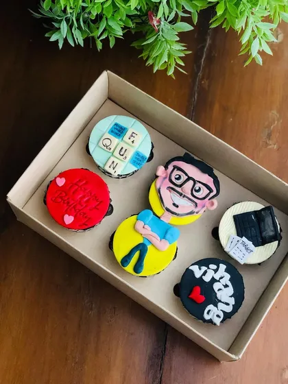I love bringing personal stories to life on cupcakes. This set was personalized for a birthday, featuring a caricature, a Scrabble board, a laptop, and his name, reflecting his hobbies and personality.
