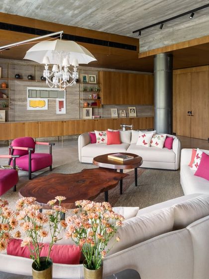The first-floor lounge in the K Residence is a playful and witty space designed for family. Pops of fuchsia and butterfly-print cushions add a touch of whimsy, balanced by the raw concrete ceiling and the organic form of the live-edge wood coffee table.