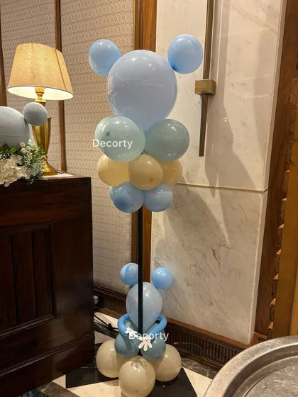A creative balloon sculpture in the shape of Mickey Mouse, using pastel blue and peach balloons to match the party's color scheme.