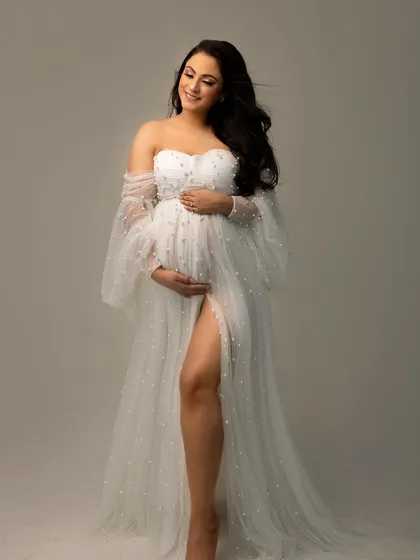 A portrait that focuses just on you and the miracle you're carrying. This mama-to-be looks absolutely radiant in a delicate, pearl-studded maternity gown, embodying pure joy.