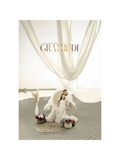 "Overflowing with GRATITUDE," this portrait captures the couple seated on a beach, surrounded by flowers and flowing white drapes. It's a beautiful expression of thankfulness for the miracle they are about to receive.