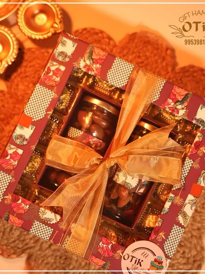 A luxurious Diwali gift box, beautifully tied with a golden ribbon. This hamper is filled with assorted chocolates and jars of premium dry fruits, perfect for festive gifting.