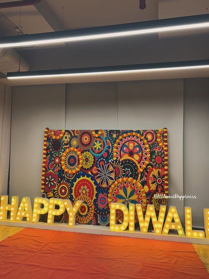 A grand "Happy Diwali" setup for a corporate office. The backdrop is made of colorful traditional elements, and the large marquee letters light up the space with festive cheer.