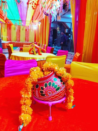 A traditional painted pot with marigold flowers, used as a beautiful and auspicious centerpiece for tables at a Haldi ceremony.