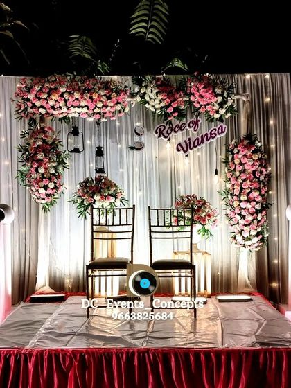 An intimate and romantic Roce decor setup for two. The backdrop of white curtains, fairy lights, and pink floral arrangements creates a dreamy and personal space for the couple.