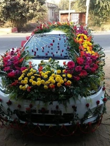 A very heavy and colorful floral decoration covering the entire hood of the car. This design uses a mix of marigolds, roses, and other flowers for a grand and traditional look.