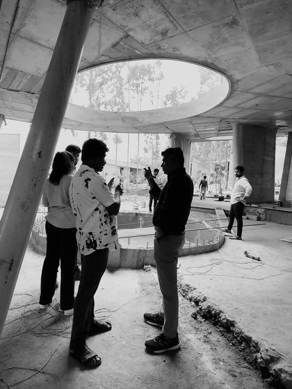 A black and white photo from a site visit, capturing a discussion amidst the raw concrete structure of a future project. This is a testament to the planning and execution that goes into every design.