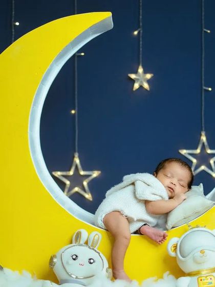 Every detail, from the plush toys to the soft lighting, is chosen to complement the 'Blue Moon' theme and create a serene environment for the newborn session.