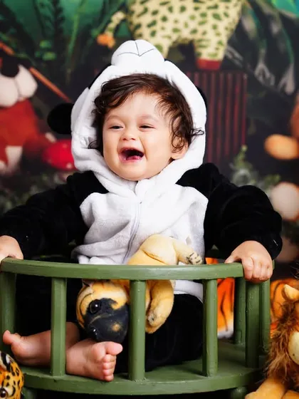 A wild one! This little boy is having a blast in his jungle-themed first birthday shoot, dressed in a panda costume and surrounded by stuffed animals.