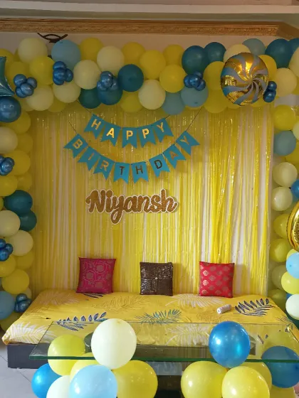 A simple and sweet home decoration for a 6th birthday. A yellow fringe curtain and a blue and yellow balloon arch create a bright and happy backdrop.