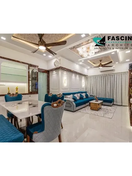 A wide view of the luxurious living and dining space at a Lodha Belair project. The design integrates a vibrant blue sofa with ornate dining furniture and a custom ceiling, showcasing our ability to blend bold colors with classic elegance.