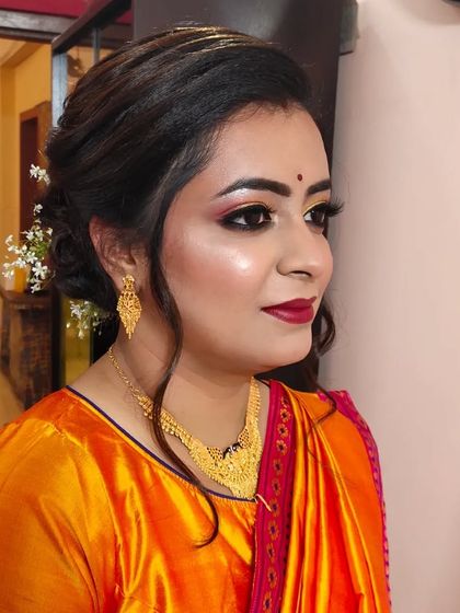 A classic party look for a client in a traditional silk saree. The makeup features golden eyes and a bold red lip, perfect for festive occasions.