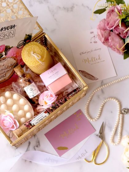 An overhead shot of a curated gift box, complete with a Nykaa skin secrets mask, pearls, and floral elements. The composition is a beautiful blend of textures and soft colors, creating a luxurious feel.