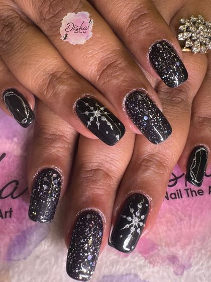 A beautiful winter-themed design with black nails, silver glitter, and delicate snowflakes.
