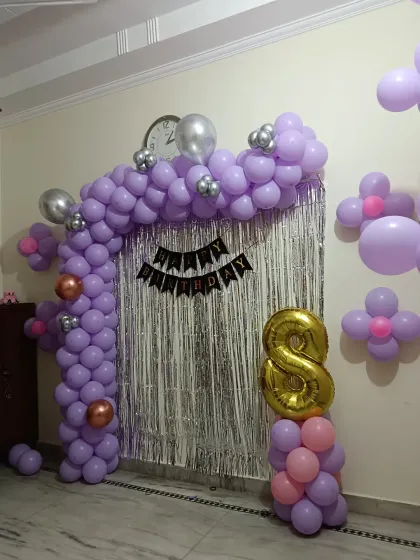 A purple and silver balloon arch with a shimmer curtain, decorated for an 8th birthday party.
