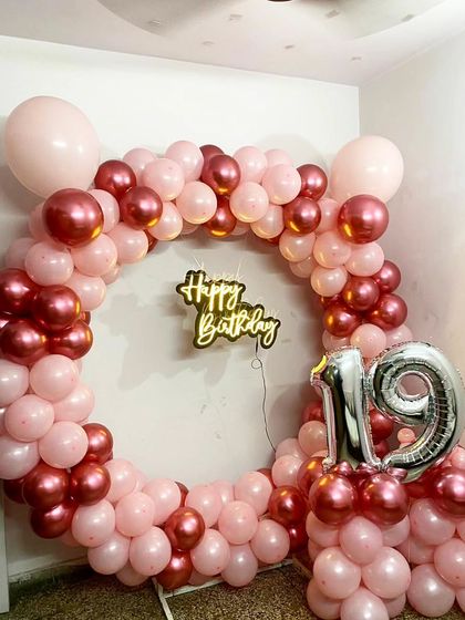 A beautiful ring backdrop made of pink and rose gold chrome balloons, with a '19' foil number accent.
