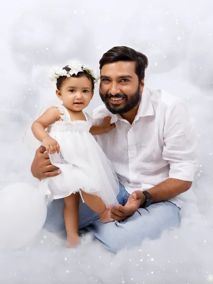 A father and his little angel share a sweet moment together amidst the clouds of their magical photoshoot.