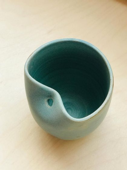 The "Sipura" cup, designed with a built-in spout for mindful sipping. This version has a smooth, matte teal glaze, perfect for a calming cup of herbal tea.