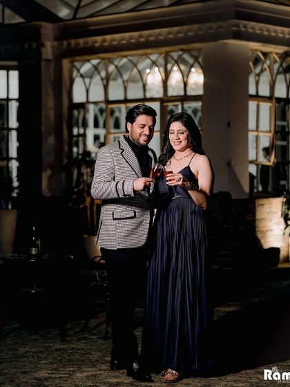 A candid moment of a couple sharing a toast at night in a beautiful glasshouse setting. The warm lighting and relaxed atmosphere make for a perfect, celebratory pre-wedding shot.