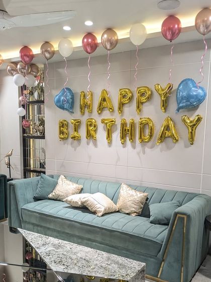 The main wall decoration with gold foil "Happy Birthday" letters, flanked by blue heart-shaped balloons and a line of ceiling balloons.