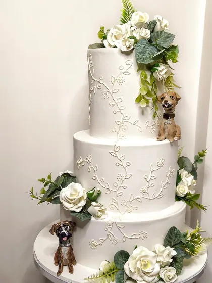 A wedding cake is personal, and nothing is more personal than including your fur babies. This elegant three-tier cake features delicate royal icing and sugar flowers, but the real stars are the custom, hand-sculpted figurines of the couple's beloved dogs, making their day even more special.