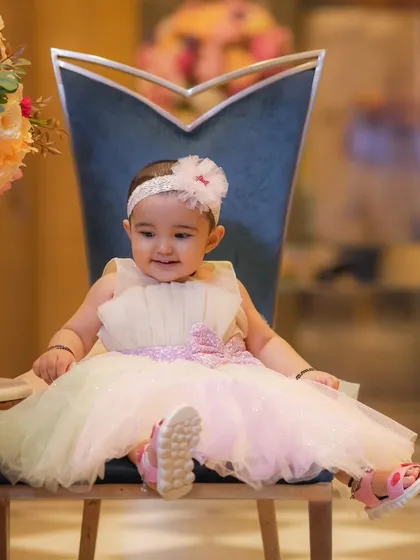 A happy, seated portrait of a baby girl in a beautiful pastel dress. Simple, elegant setups allow the child's bright personality to shine through.