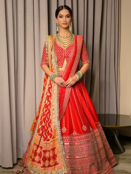 A full view of a traditional bridal look, showing how the makeup complements the entire ensemble. The skin is kept fresh and dewy to balance the richness of the red lehenga and heavy polki jewellery.